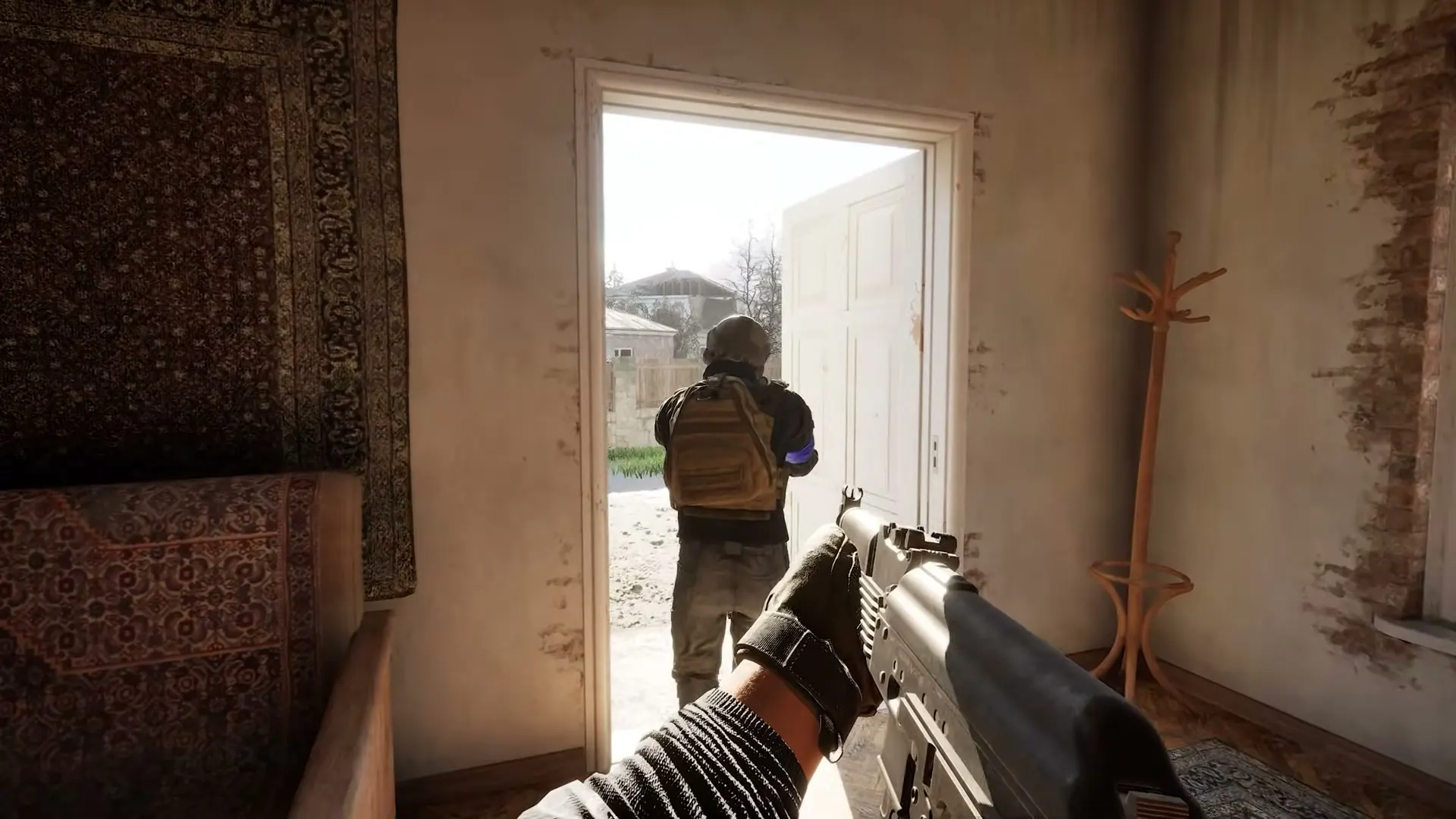 A WARDOGS operator watching a teammate leave a damaged house